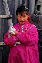 Mansi child in traditional dress holding rabbit, Siberia, Russia