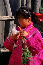 Mansi child in traditional dress feeding rabbit, Siberia, Russia