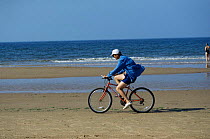 Cyclist on Holkham beach, Norfolk, England, UK