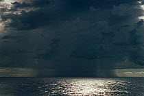 Rain squall and clouds over sunlit sea