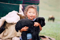 Mongolian girl holding goar kid, Hangay mountains, Mongolia.