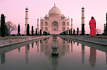 Famous landmark, the Taj Mahal with Indian woman in traditional sari, at sunrise, Agra, Uttar Pradesh, India