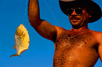 Man with Piranha caught on fishing line {Piranha sp} Pantanal, Brazil.