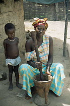 Gambian women crushing millet, with child watching, Gambia, West Africa