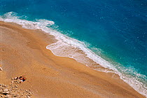 View down onto beach and sea, with people sunbathing. Kaputas, Turkey.