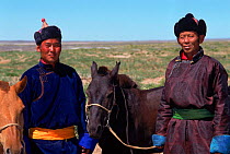 Portrait of two tribal men with horses. Gobi Desert, Mongolia.