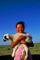 Portrait of young girl with domestic lamb. Gobi Desert, Mongolia.