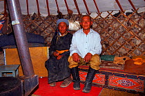 Elderly couple sitting inside felt-lined yurt (tent) Gobi Desert, Mongolia.