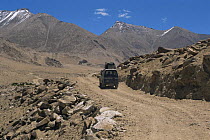 Land Rover travelling along track through valley. Ladakh, NE India