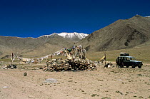 Land Rover and people next to prayer flags and 'ovoo' rock piles, Ladakh, North East India