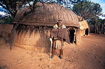 Zulu elder in traditional dress outside hut, Shackland cultural village. Kwazulu-Natal, South Africa