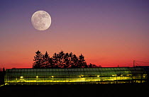 Illuminated greenhouse at dusk with moon, Germany
