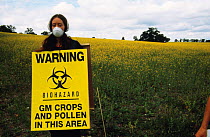 Protester with Biohazard warning sign for genetically modified (GM) oil seed rape test crop, Model Farm, Watlington, Oxfordshire, UK 1999