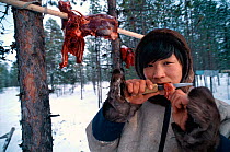 Vasja Prokofiev, 17, eating raw reindeer meat, Nentsy, Kanin Peninsula, W Arctic Russia.