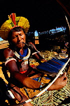 Kayapo warrior making head dress from parrot feathers, Amazon, Brazil