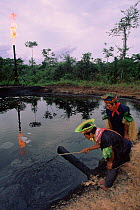 Cofan Indians inspecting oil waste pit. Amazonian Ecuador