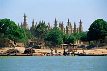 Mosque on Niger river, locals doing their washing on riverbank, Mali. West Africa