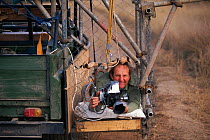 Mike Richards filming in cage beside vehicle Africa
