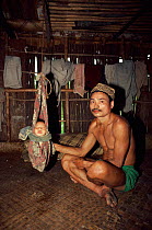 Ot Danum tribesman rocking baby in hut West Kalimantan, Borneo. Indonesia