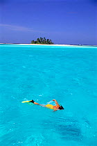 Woman snorkelling at sea surface,Cocos Keeling Island in background, Indian Ocean, Australia