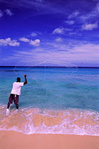 Fisherman throwing fishing net on tropical beach,  Barbados, Caribbean