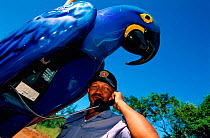 Police officer in macaw shaped telephone booth Pantanal, Brazil