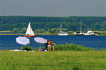 Family having a picnic beside canal with boats going past, Walcher, Beveland, The Netherlands