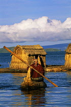 Uros, floating reed islands, and man on traditional Totora reed boat, Lake Titicaca, Bolivia/Peru, South America