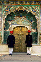 Royal guards standing on duty outside ornate gate to City Palace, Jaipur, Rajasthan, India