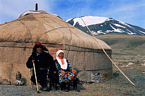 Kazakh nomad couple with Lanner falcon {Falco biarmicus} used for hunting, sitting outside their ger / yurt / tent home,  Tsengel, Western Mongolia. 2001