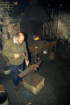 Farrier making horse shoes at forge. Wiltshire, UK. Ken May.