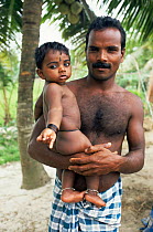 Indian man holding  child Kerala, southern India