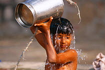 Young boy taking a bucket bath at well, Keoladeo Ghana NP, Bharatpur, Rajasthan, India