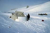 Inuit builds a snow wall round his tent for storm protection, Admiralty Inlet, Baffin Island, Canadian Arctic
