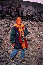 Aleut boy holding Crested auklet shot for food, Little Diomede Aleut Community, Bering Sea, Alaska, USA 1999