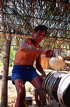 Man curing rubber in traditional way, Tambopata river, Peru, South America