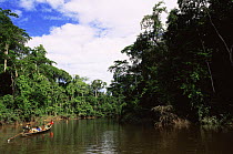 Local family travelling in canoe down Madre de Dios river, Peru, South America