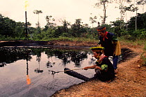 Cofan Indians inspecting waste pit, Rio Agua Rico, Dureno, Ecuadorian Amazon