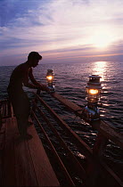 Bamboo raft occupied by Rakit custodian who attracts fish from deep waters with lanterns at night for fishermen to catch at dawn. Boats pay to fish in a Rakit area. 2000 Indonesia
