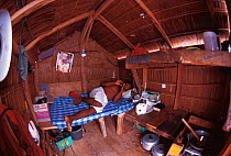 Custodian inside a Rakit, Indonesia. Hut on small bamboo raft. Custodian attracts fish from deep waters with lanterns at night for other fishing boats to catch at dawn. Boats pay to fish. 2000