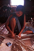 Bajau woman weaving mats, Malaysia. Bajau people live in houses on stilts or are nomadic in houseboats. 2000