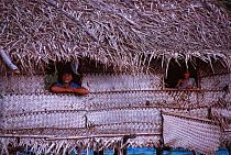 Bajau women look out of stilt house, Malaysia. Bajau people live in houses on stilts or are nomadic in houseboats. 2000