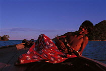 Bajau boy playing banjo, Malaysia. Bajau people live in houses on stilts or are nomadic in houseboats. 2000