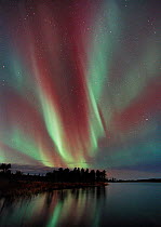 Aurora borealis colours in night sky over lake, northern Finland , October 2002