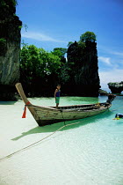 Traditional long tail boat and child in bay. Krabi, Hong Island, Thailand