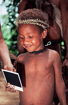Young Huli boy looking at polaroid photo of himself, Central Highlands, Papua New Guinea