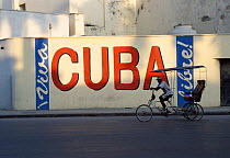 Man on rickshaw cycling past Cuba sign, Old-Havana, Havana, Cuba Caribbean