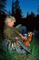Fisherman with dog at lake in evening. Trout fishing. Norway
