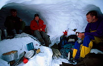 Melting snow for cooking inside a snow hole shelter. Finse, Hardangervidda, Norway