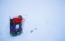 Girl emerging from snow hole shelter. Finse, Hardangervidda, Norway